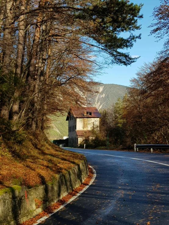 an empty street leading to a building surrounded by trees