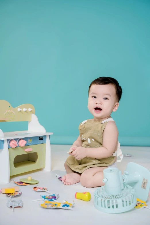 a baby sitting on the floor next to a toy oven