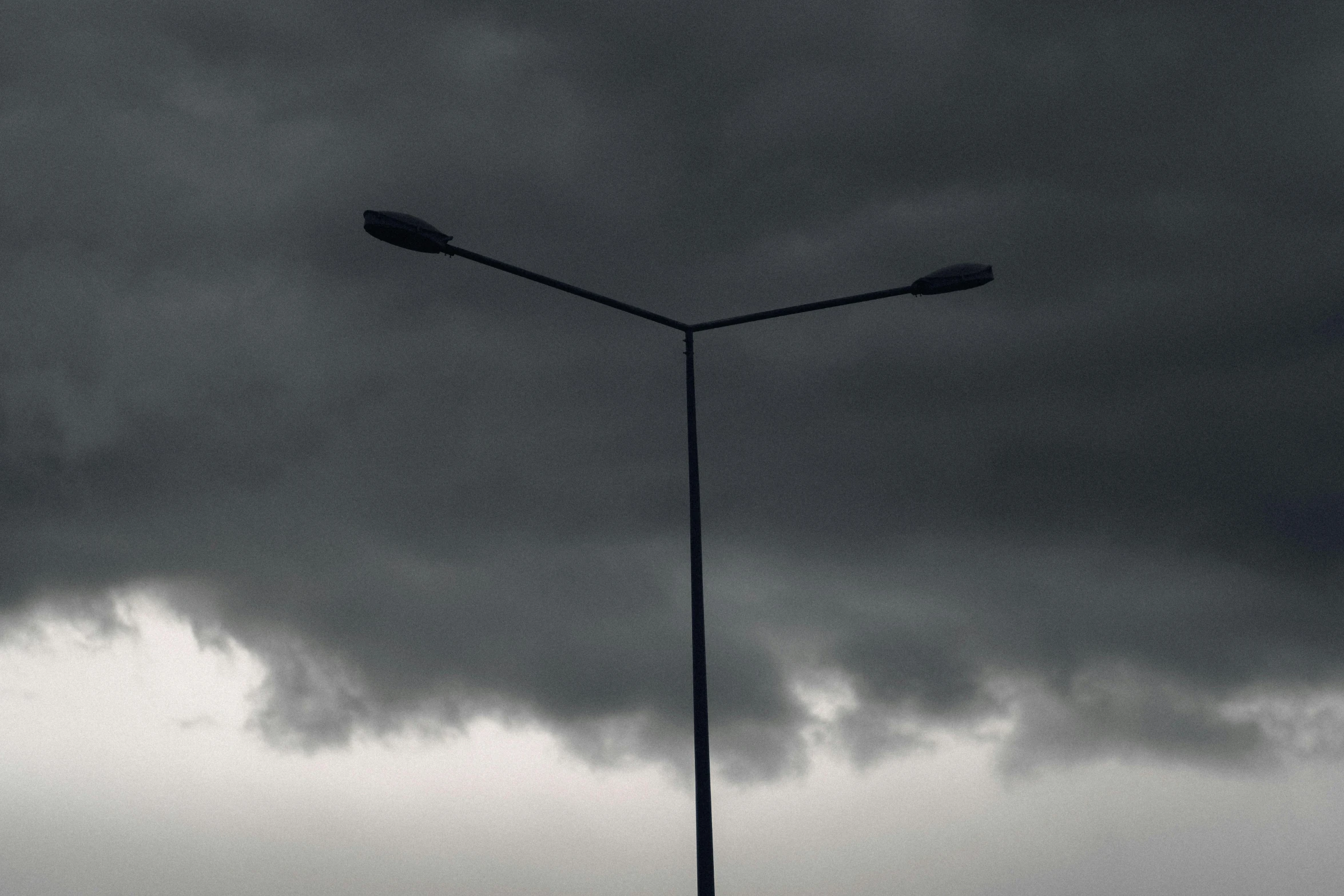 a streetlight and pole beneath a storm cloud