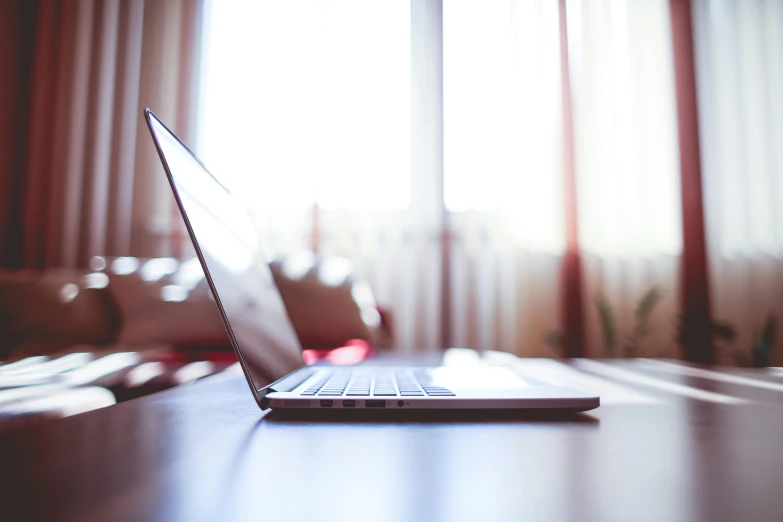 an open laptop computer sitting on top of a wooden table