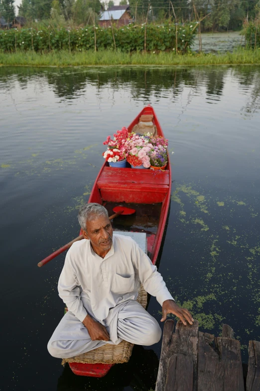 man standing near red boat with flowers on it
