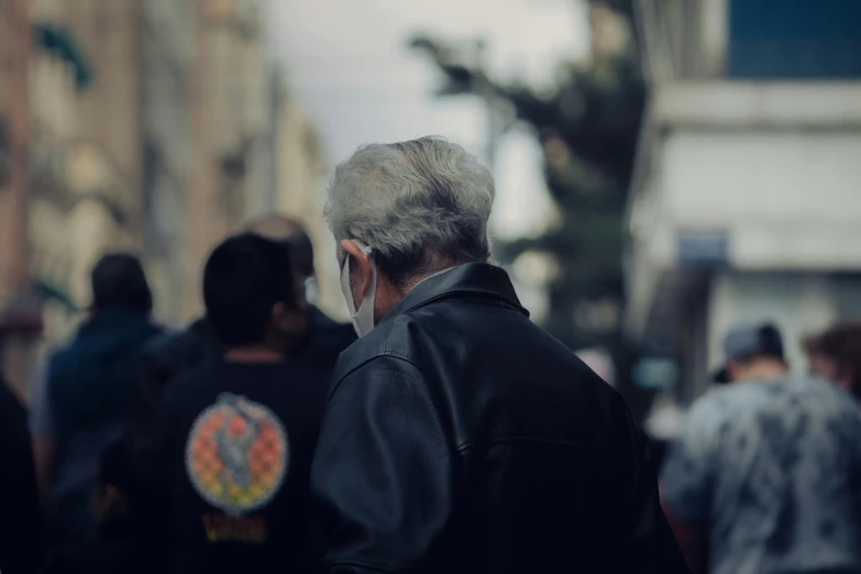 a man with grey hair walking down a busy street