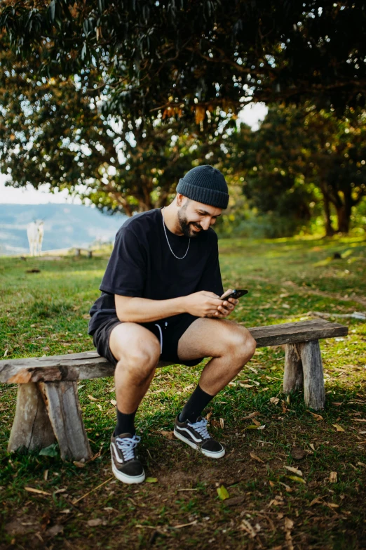 a man in shorts and hat sitting on a bench