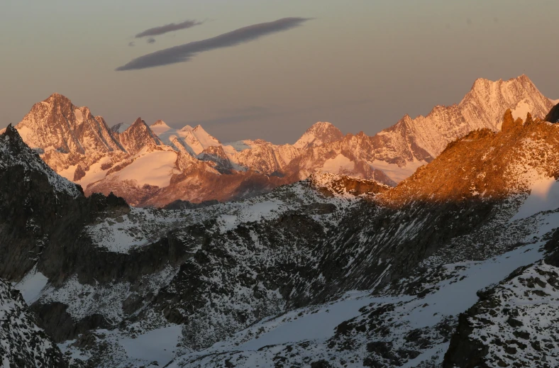 some mountains covered in snow with one small cloud in the sky