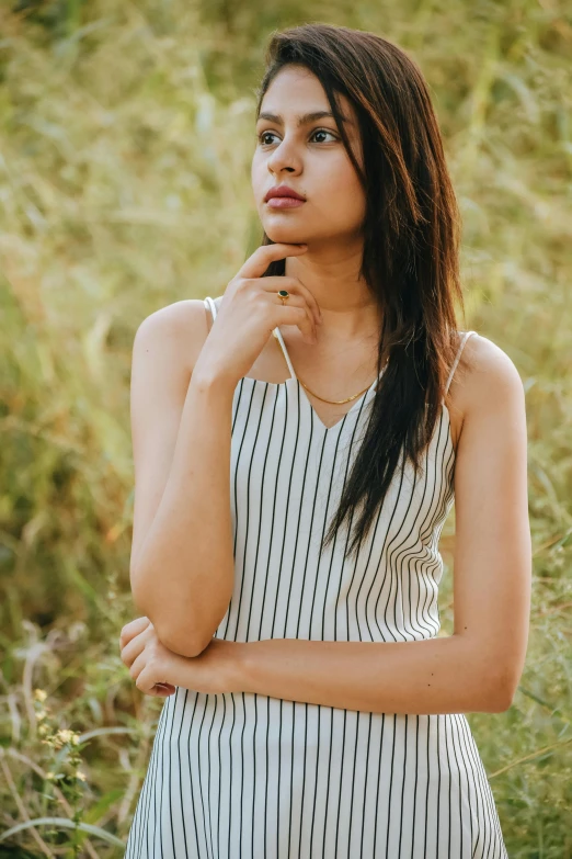 a young lady in striped shirt standing in a field