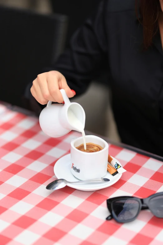 a woman pouring coffee in to a cup on a plate