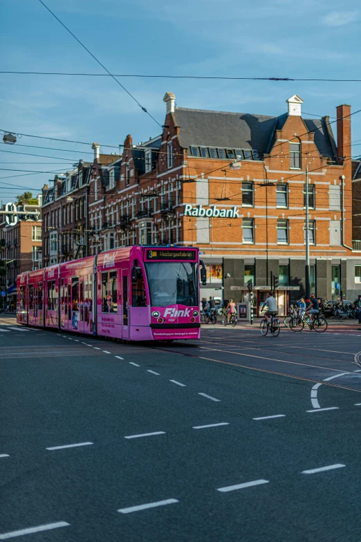 pink city tram travelling down street in city