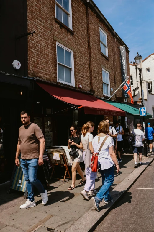 people walk past a building on a busy street