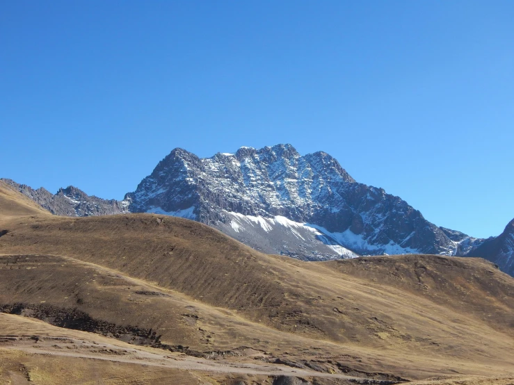 the mountain range is covered in snow with some brown and yellow vegetation