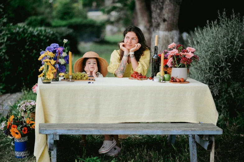 two women sit at a table with a flowered garden and plants on it