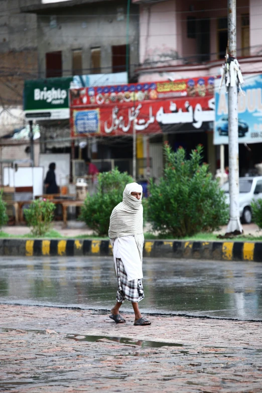 an old man stands in the rain on the sidewalk