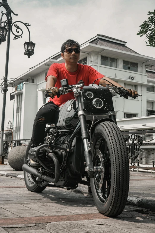 man wearing red t - shirt on a black motorcycle