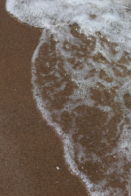 the tide is hitting the shore with bubbles