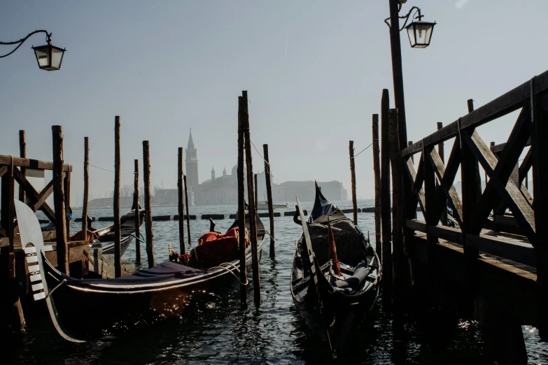 several gondolas are moored to poles on the water