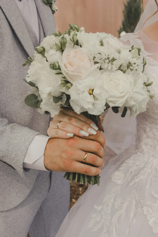 bride and groom holding bouquet of white flowers