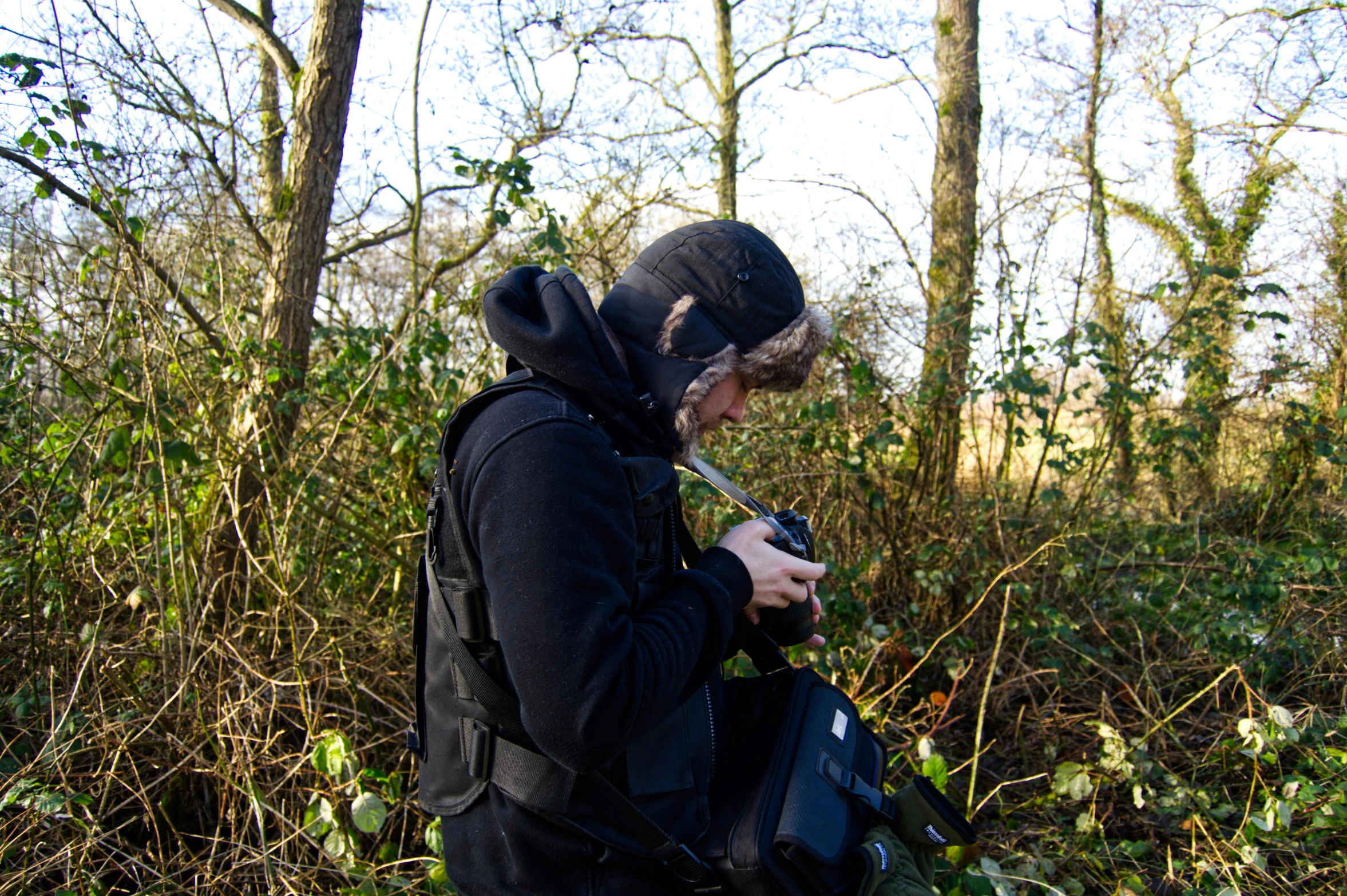 a man with a backpack is in the woods holding a knife