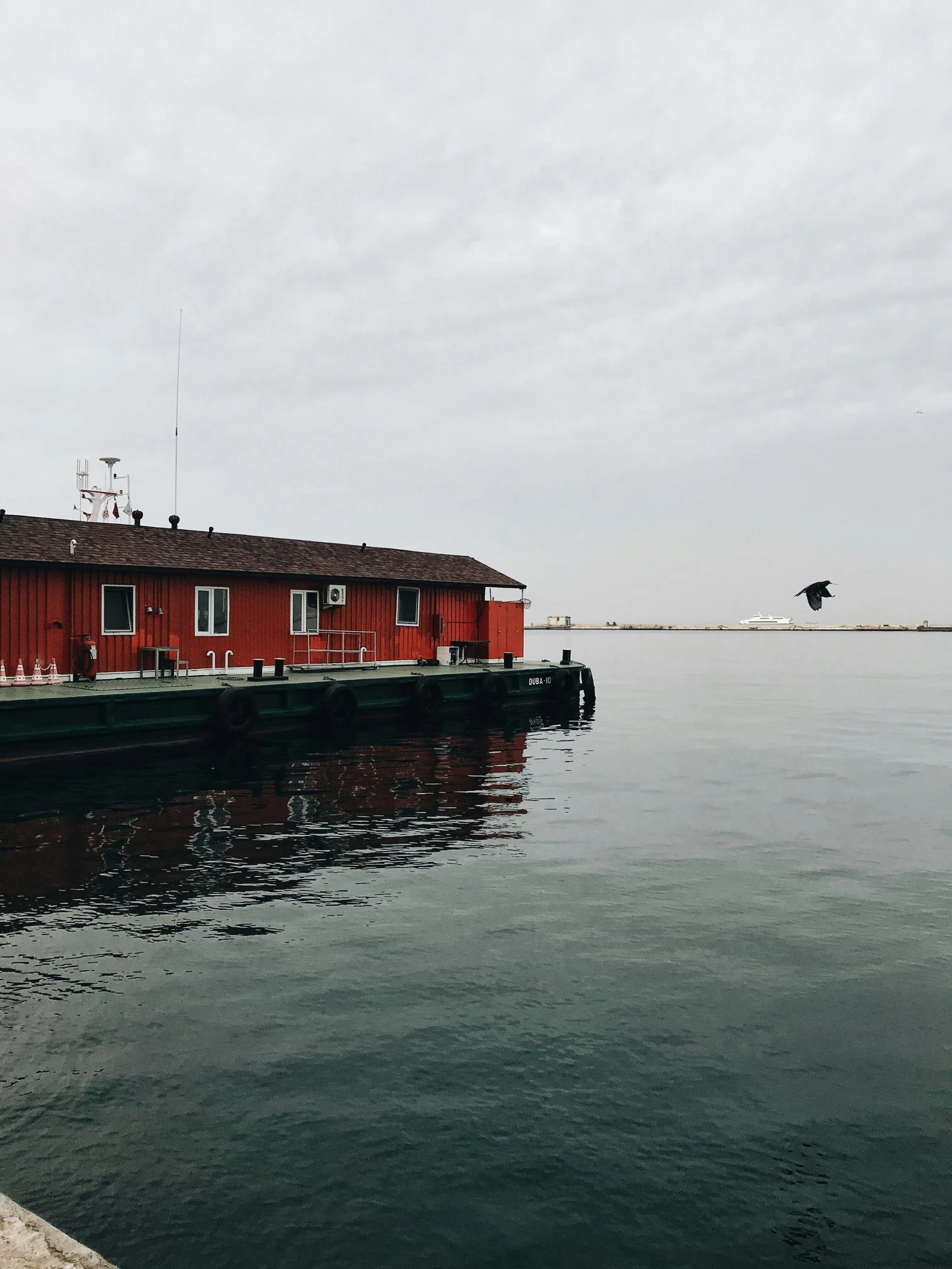 a small boat floating on top of water next to a red building