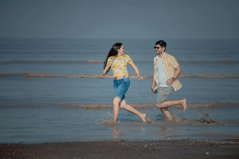 a couple running through the ocean with one woman holding the other hand