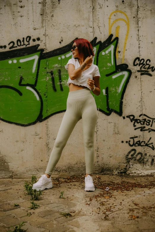 a woman stands in front of graffiti covered wall