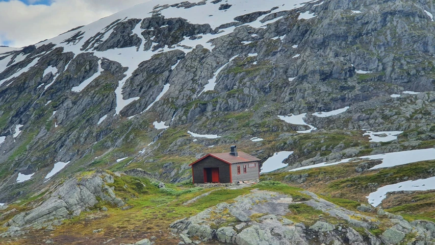 a small cabin set on the base of a snowy mountain