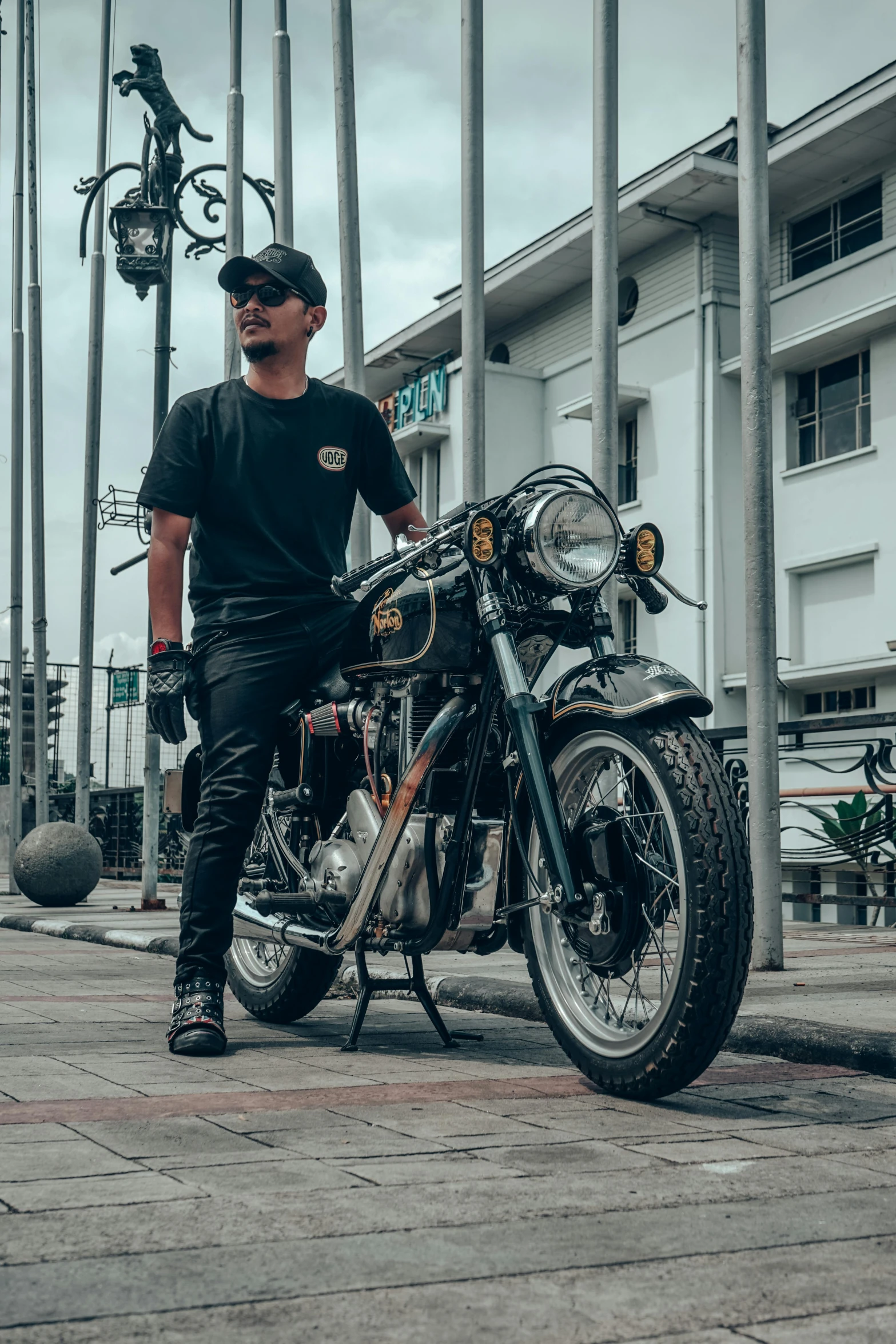 a man sits on his motorcycle next to a row of palm trees