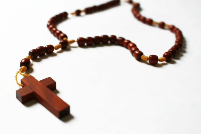 a wooden rosary with a red and gold bead