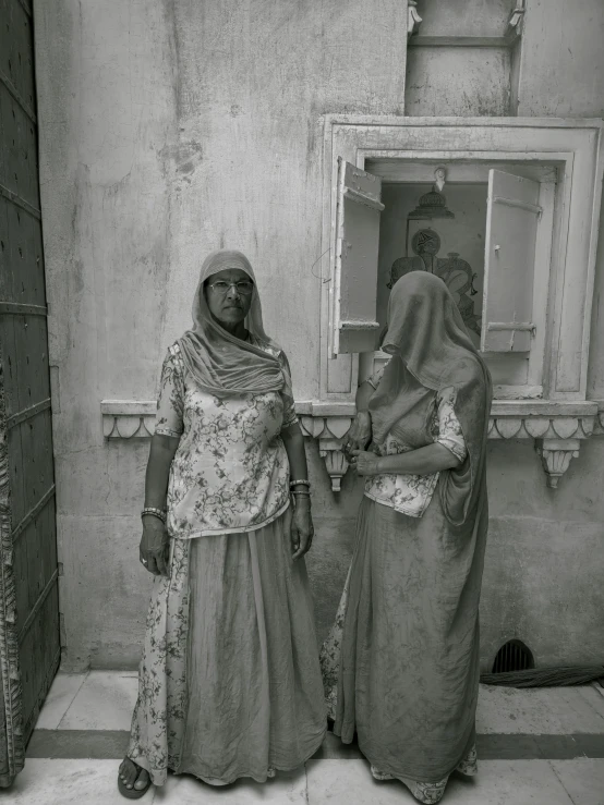 two women standing next to each other near a window