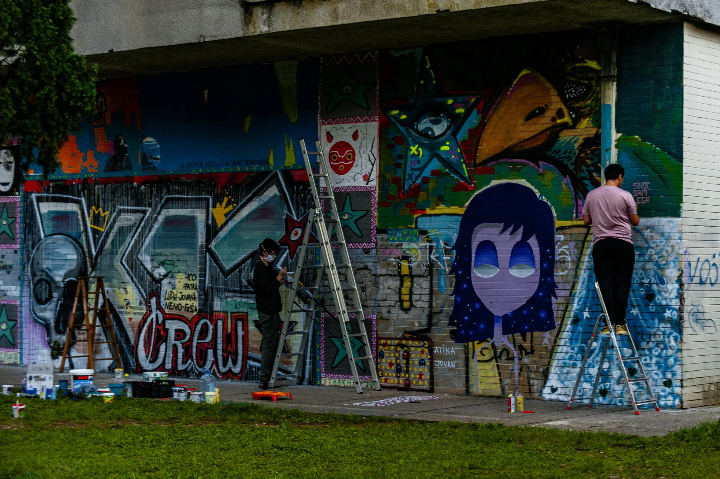 men are painting the side of a building on the street