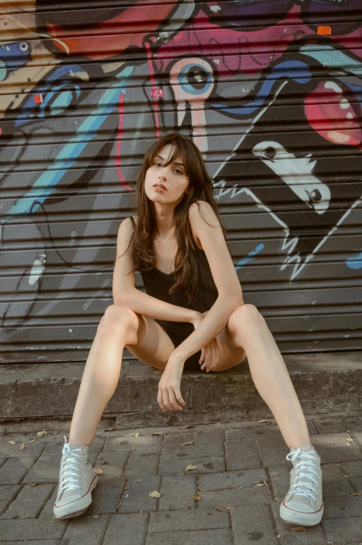 a  sits on the sidewalk in front of a graffiti covered wall