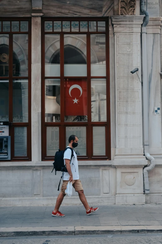 a man walks on the side of a street in front of a building with large doors