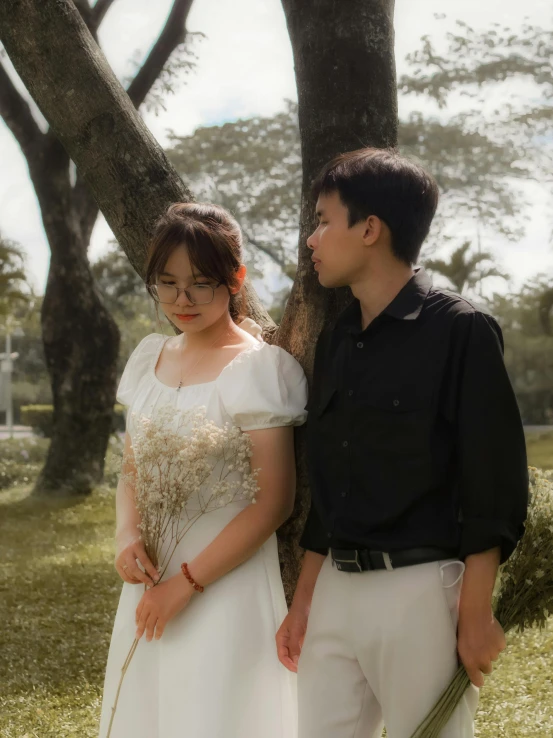 the man and woman are posing in front of a tree