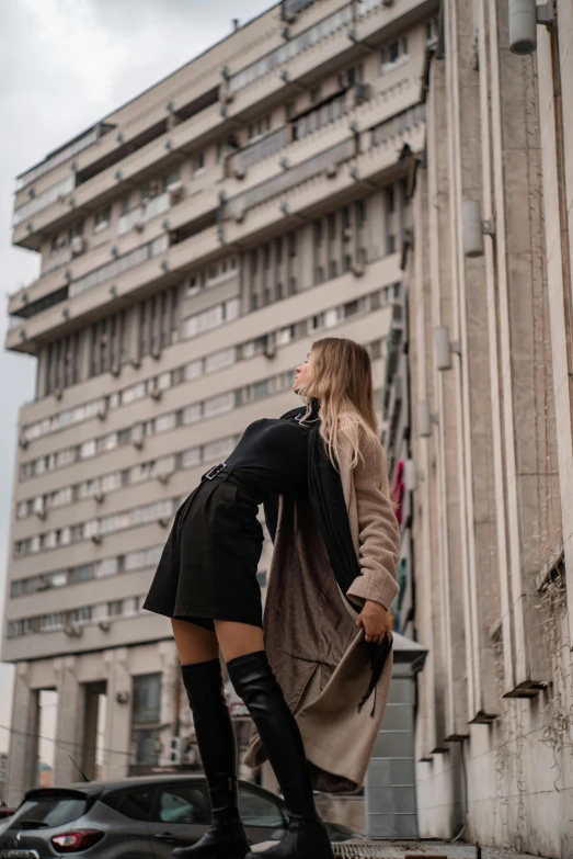 a woman is leaning against a tall building