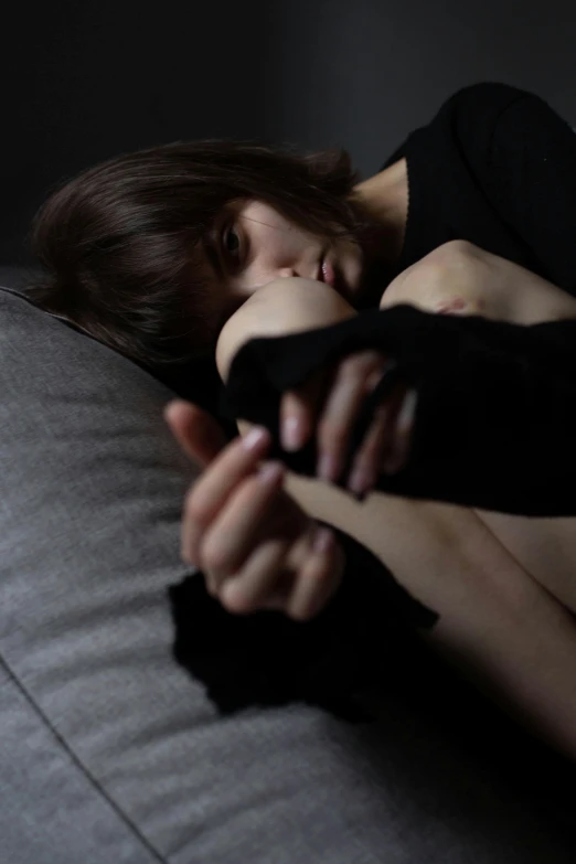 a woman holding onto an object while lying on the couch