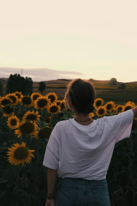 the back view of a woman looking at sunflowers