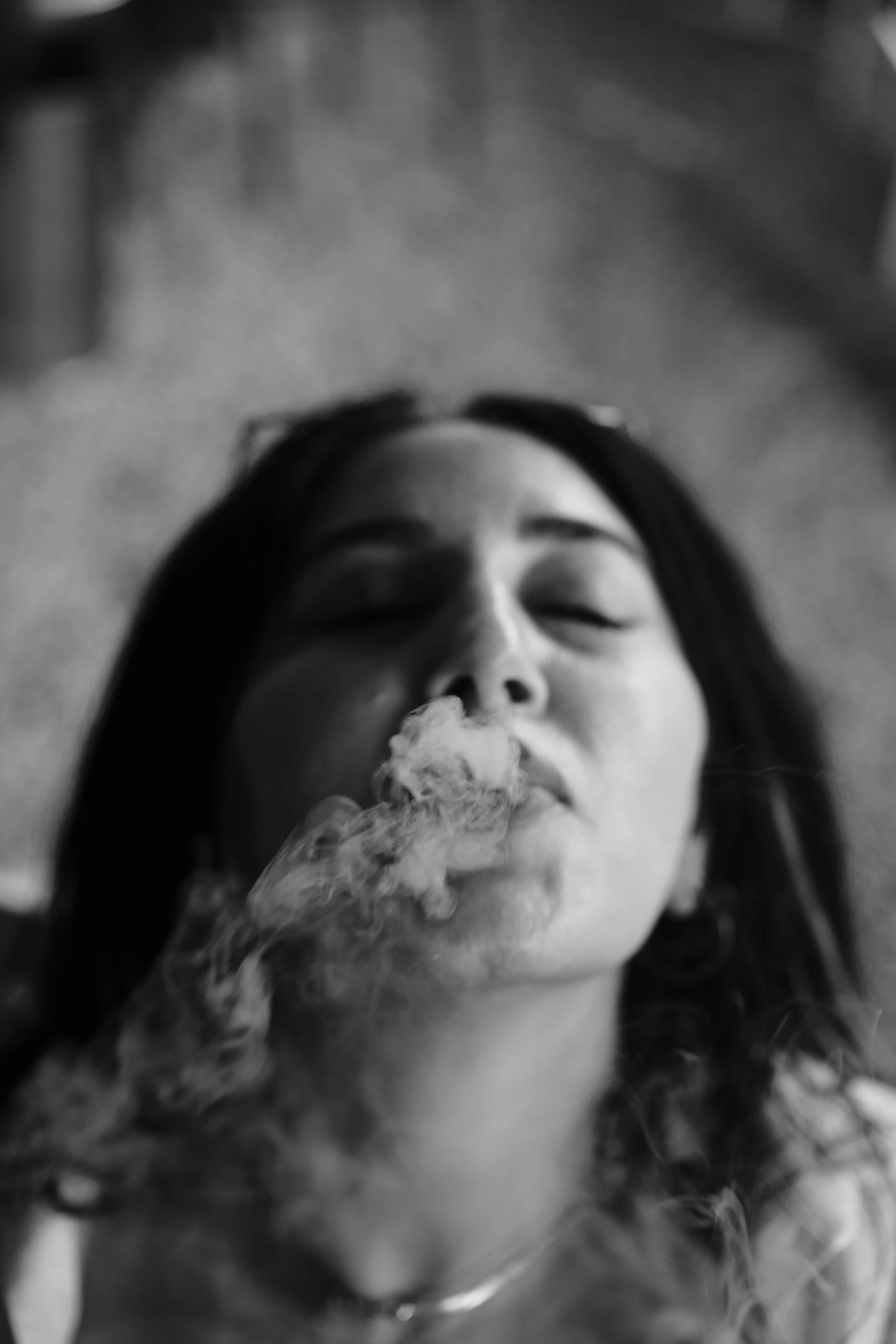 a woman blows up smoke from her nose