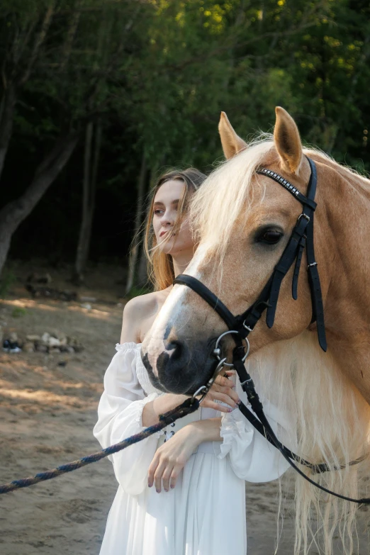 a beautiful woman in white posing next to a brown horse