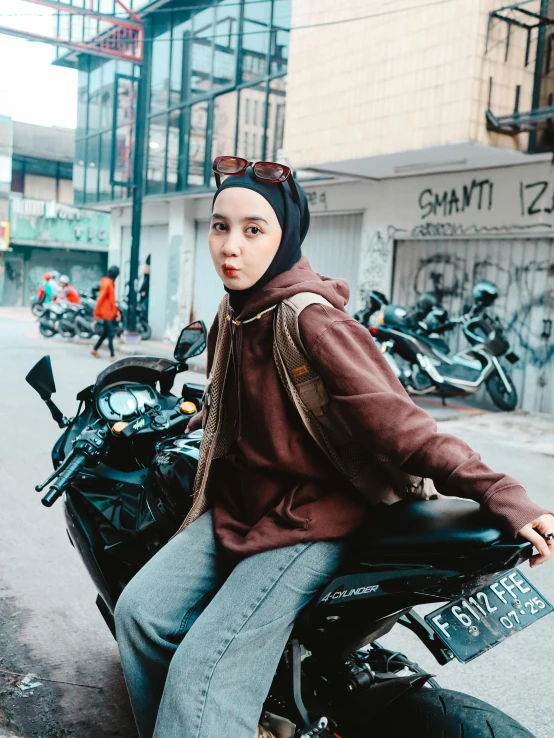 a woman in a black hat sitting on a motorcycle