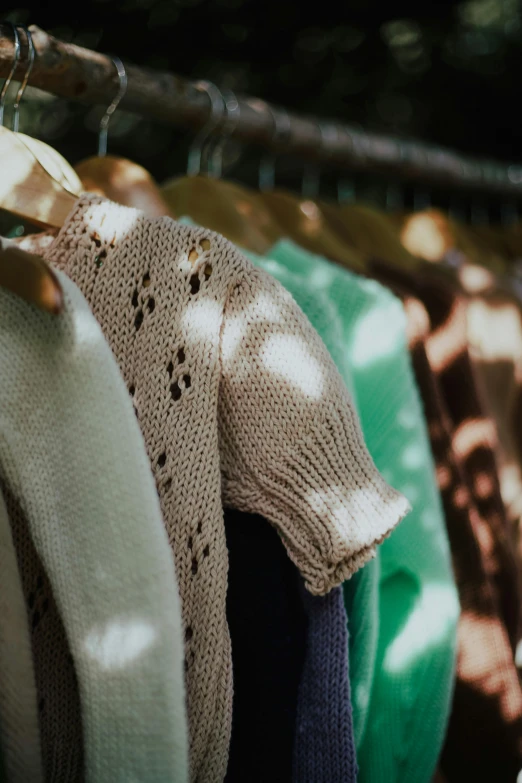 several sweaters are hanging in a rack together