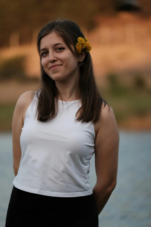 a woman posing for a po wearing a white top and a flower in her hair