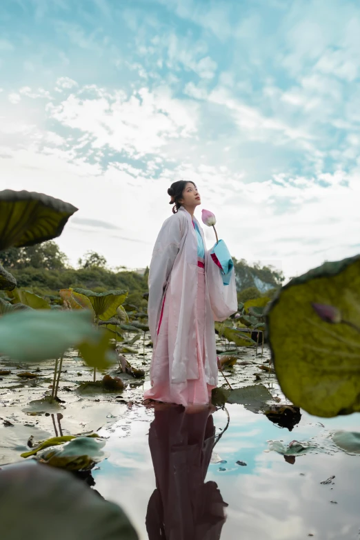 an asian woman wearing traditional chinese clothing stands in a pond