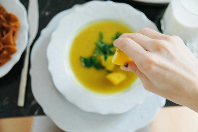 a person eats soup out of an empty white bowl