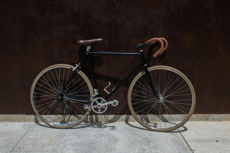 an old bicycle stands against a brown wall