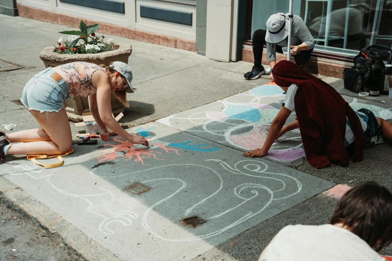 children are drawing on sidewalk with chalk with flowers and shapes