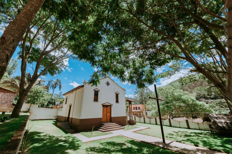 a small white building in the shade of trees