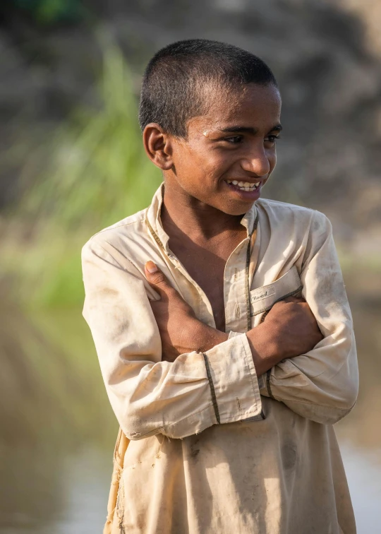 a smiling man with his arms crossed by the water