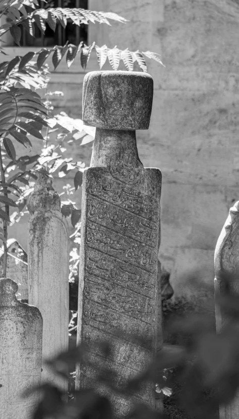 a garden filled with tall stone headstones and plants