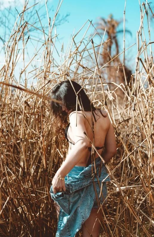 a woman in high heels and jeans is standing in a field of tall grass