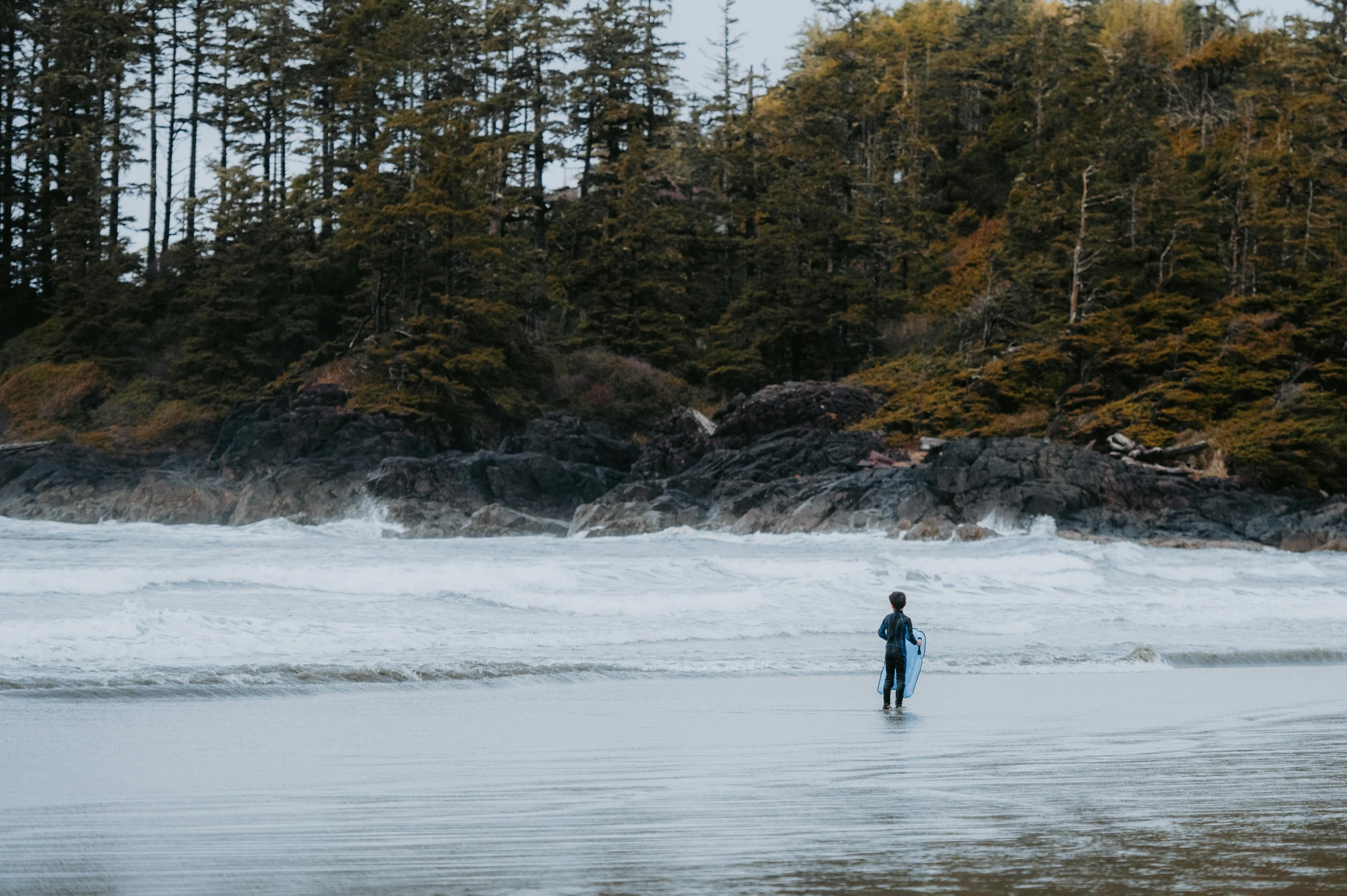 a person with a blue surfboard standing on a beach