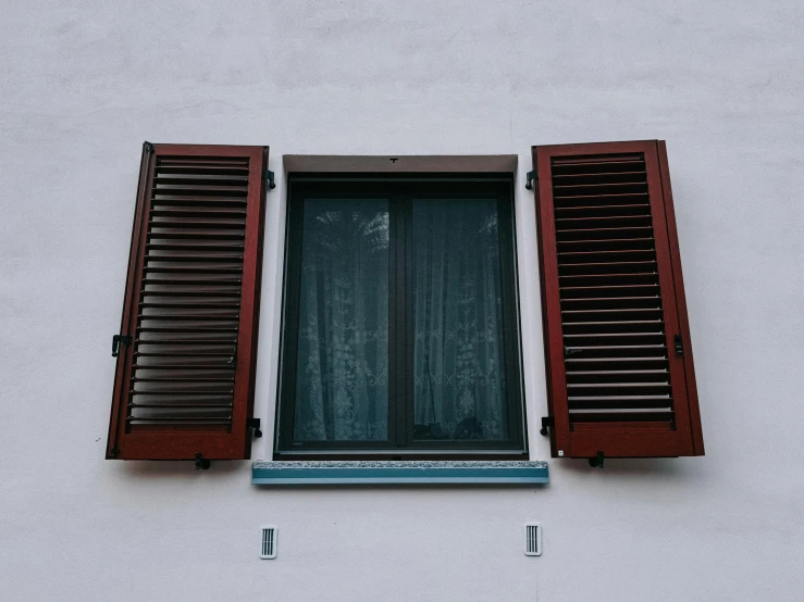 an open window with wooden shutters and blue trim