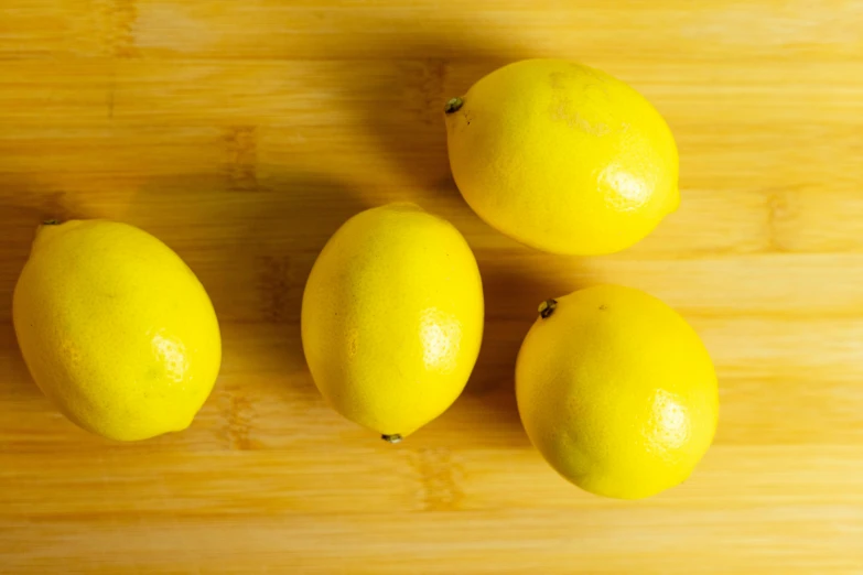 three yellow lemons sit next to each other on a  board